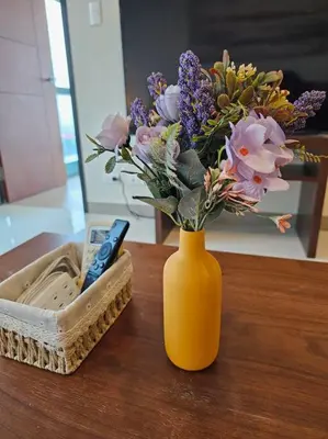 a yellow vase with flowers in it on a table at One Uptown BGC Modern & Spacious, Great Location, 200mbps & washer in Manila