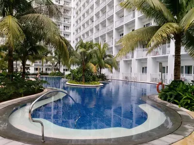 a large swimming pool with palm trees in front of a building at Mi Casa in Manila