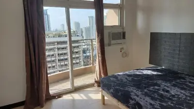 a bedroom with a window with a view of a city at Hospital ng Manila front delux le mirage de malate in Manila