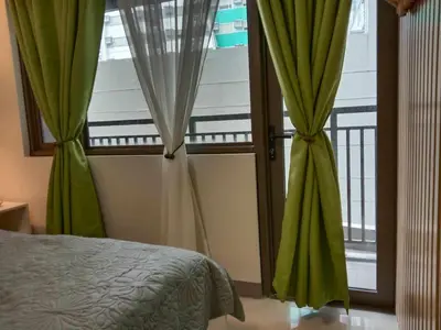 a bedroom with a bed and a window with green curtains at OASIS CHIC By THE BAY PASAY CITY Near Mall of Asia in Manila