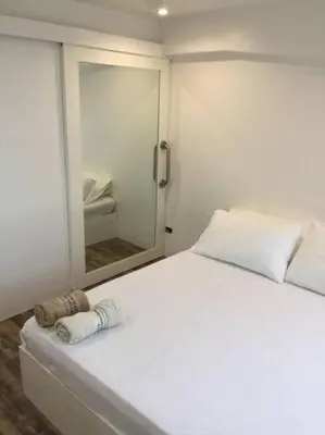 a bedroom with a white bed and a mirror at Renovated 2br 2tb Wifi/Netflix very near Mall QC in Manila