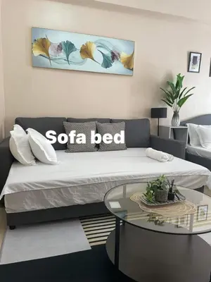 a living room with a sofa bed and a glass table at studio condo building 81 newport boulevard in Manila