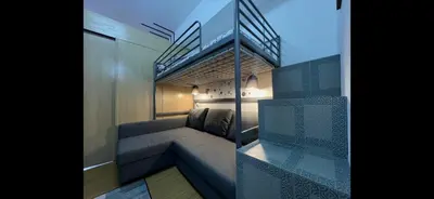 a small room with a couch and a staircase at H&H at Grace Residences in Manila