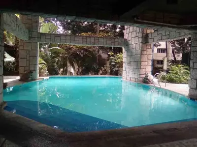 a large swimming pool with blue water under a stone wall at Cozy35sqm w parking balcony Wifi/Netflix near Mall in Manila