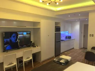 a living room with a flat screen tv and a kitchen at Cozy35sqm w parking balcony Wifi/Netflix near Mall in Manila