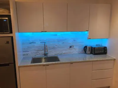 a kitchen with a sink and a counter with blue lighting at Cozy35sqm w parking balcony Wifi/Netflix near Mall in Manila