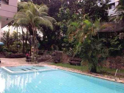 a large swimming pool with palm trees and a building at Cozy60sqm 1BR balcony/prking/Wifi/Ntflix near Mall in Manila