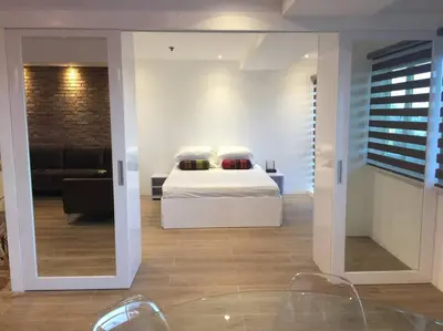 a bedroom with a bed and a living room at Cozy60sqm 1BR balcony/prking/Wifi/Ntflix near Mall in Manila