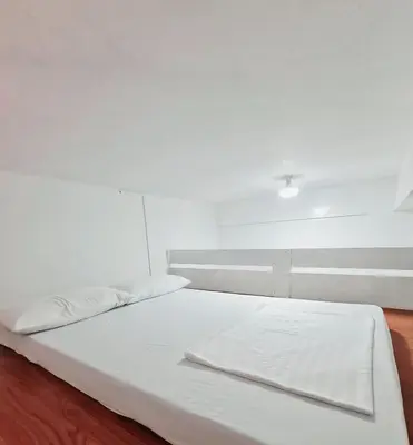 a white bed in a room with a white wall at Dasma Lofts Hotel near Dela Salle Dasma in Dasmariñas