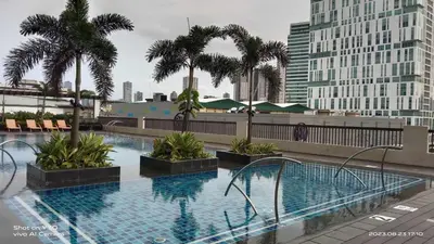 a large swimming pool with palm trees and buildings at SonSon at Manhattan Plaza Tower 1, Araneta, Cubao, Quezon City in Manila