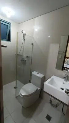 a white bathroom with a toilet and a sink at Hilander's Condotel near Terminal 3 Airport in Manila
