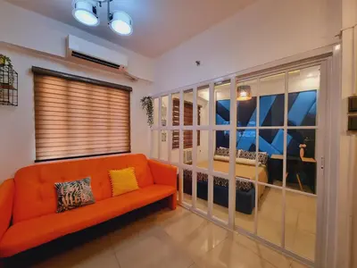 a living room with an orange couch and a window at Modern Minimalist Condo near Airport in Manila