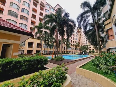 a hotel courtyard with palm trees and a swimming pool at Modern Minimalist Condo near Airport in Manila
