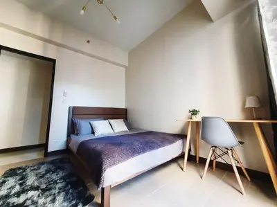 a bedroom with a bed and a desk and a chair at Beautiful High End Condo in City Center, Manila in Manila