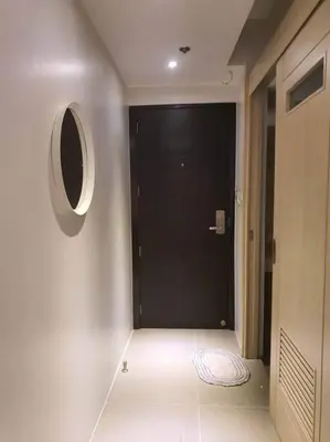 a hallway with a black door and a mirror at Cozy Studio with Beautiful View & FREE Netflix Access in Manila