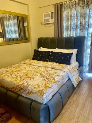 a bed in a bedroom with a blue and yellow blanket at 2BHK with Balcony Fully Furnished-70sqm Condo Pasig in Manila