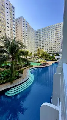 a resort swimming pool with palm trees and buildings at ART's Nest at Shore Residences in Manila