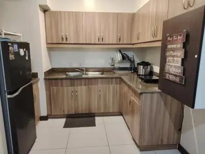 a kitchen with wooden cabinets and a black refrigerator at Acacia Estates Taguig in Manila