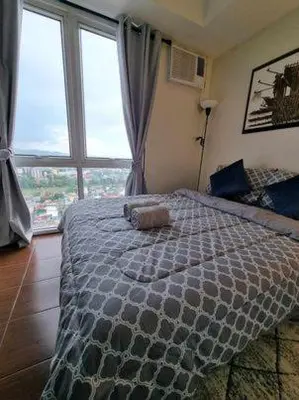 a bedroom with a large bed with a large window at Casa REYNA at KASARA Urban Residences in Manila