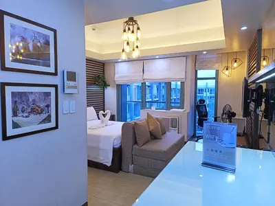 a hotel room with a bed and a couch at Two Palmtree Villas Across Manila Airport Terminal 3 -JJRMK Condotel in Manila