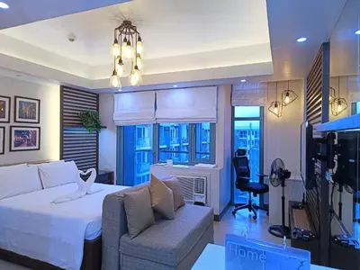 a hotel room with a bed and a chair at Two Palmtree Villas Across Manila Airport Terminal 3 -JJRMK Condotel in Manila