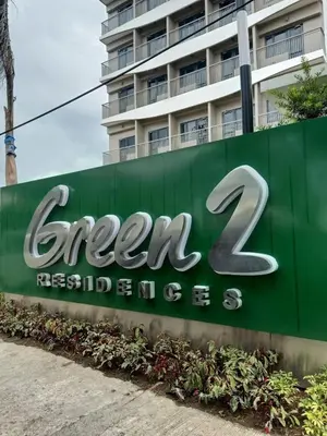 a green sign for a hotel with a building in the background at Suzi's Place @ Green 2 Residences Free Wi-fi & Netflix in Dasmariñas