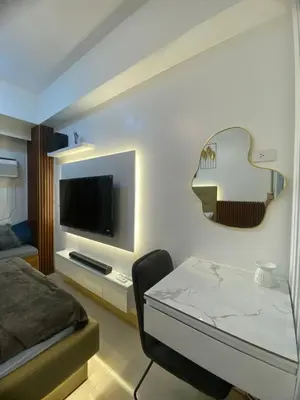 a room with a bed and a table with a television at Suzi's Place @ Green 2 Residences Free Wi-fi & Netflix in Dasmariñas