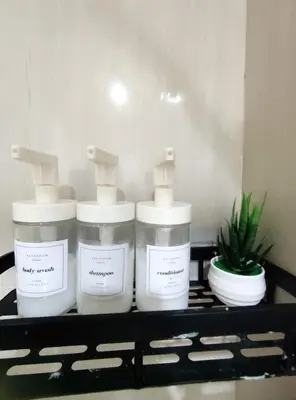 three bottles of soap on a shelf with a plant at Shell res nr MOA 2BR free parking in Manila