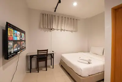 a bedroom with a bed and a tv and a chair at JP Santiago Studio Makati J304 in Manila