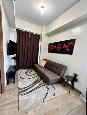 a living room with a brown couch and a rug at Staycation at Spring Residences in Paranaque in Manila