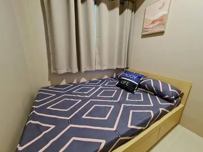 a bedroom with a bed with a blue comforter and pillows at Chic 2 Bedroom EDSA APT with Balcony in Manila
