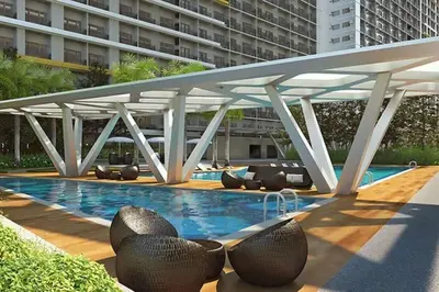a swimming pool with chairs and a large building at Chic 2 Bedroom EDSA APT with Balcony in Manila