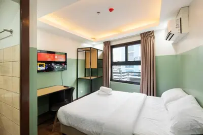a bedroom with a bed and a desk and a window at St. Marvin Studio Makati M204 in Manila