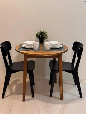 a wooden table with two chairs and a table with dishes on it at Morgan Suites Executive Residences in Manila