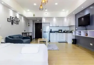 a living room with a bed and a kitchen with a couch at Cozy condo with balcony in Taguig in Manila