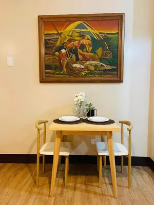 a table and chairs with a painting on the wall at Richjones Bed & Breakfast in Manila