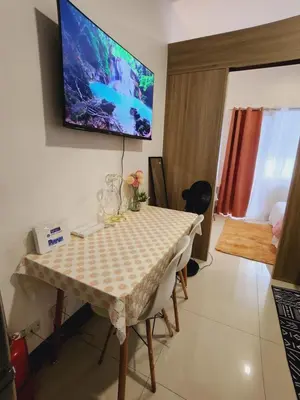 a dining room with a table and a television on the wall at Fame Residences Staycation in Manila