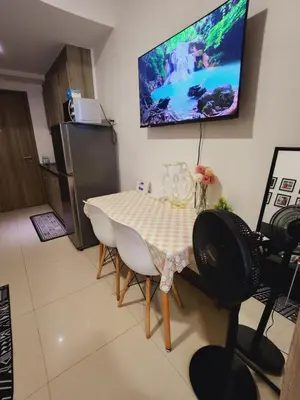a dining room with a table and a television on the wall at Fame Residences Staycation in Manila