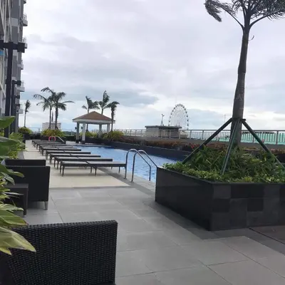 a pool with benches and a ferris wheel in the background at LJ'S Escape 1BR Coast Residences in Manila