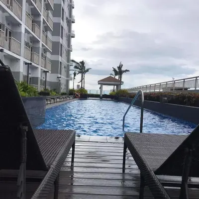 a swimming pool in the middle of a building with two benches at LJ'S Escape 1BR Coast Residences in Manila