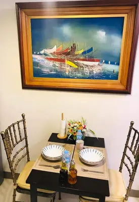 a table with two chairs and a painting of a boat at LJ'S Escape 1BR Coast Residences in Manila