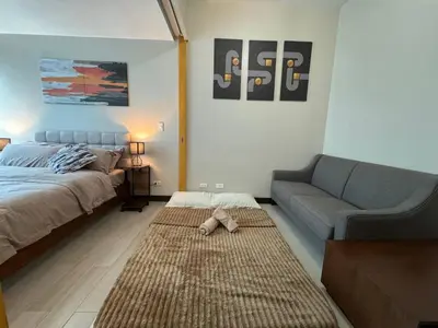 a living room with a bed and a couch at Modish 1BR One Uptown BGC direct to Uptown Mall in Manila