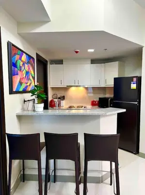 a kitchen with three chairs and a counter with a refrigerator at Cozy 2 Bedrooms in BGC with Balcony Bathtub 600Mbps in Manila