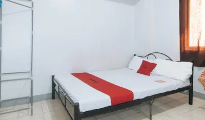 a small bed with a red and white blanket on it at MCP Transient near NAIA in Manila