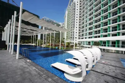 a pool with white chairs next to a building at Manila Philippines, Azure Urban Resort Staycation by Leroche near Ninoy Aquino International Airport in Manila