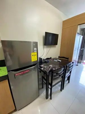a kitchen with a table and a television in a room at Shell Residence Moa - Anne in Manila