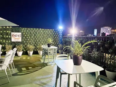 a patio with tables and chairs and potted plants at night at Nest Fort BGC in Manila