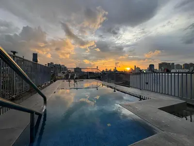 a swimming pool on top of a building with the sunset at Nest Fort BGC in Manila