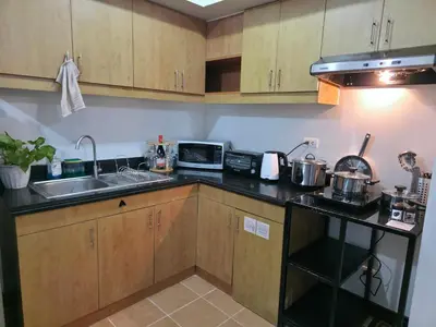 a small kitchen with a sink and a microwave at Acacia Estates' The Getaway Taguig Jade Tower in Manila