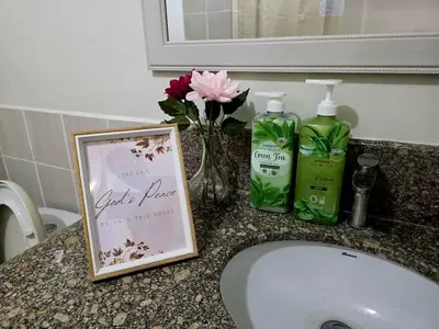 a bathroom sink with a picture and two bottles of soap at Acacia Estates' The Getaway Taguig Jade Tower in Manila